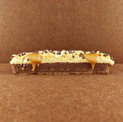 Primer plano de una Tarta Ópera cuadrada, resaltando la textura del glaseado chocolate, la suavidad de la crema de café, la cremosidad de la ganaché de chocolate y la esponjosidad del bizcocho gioconda empapado en café.