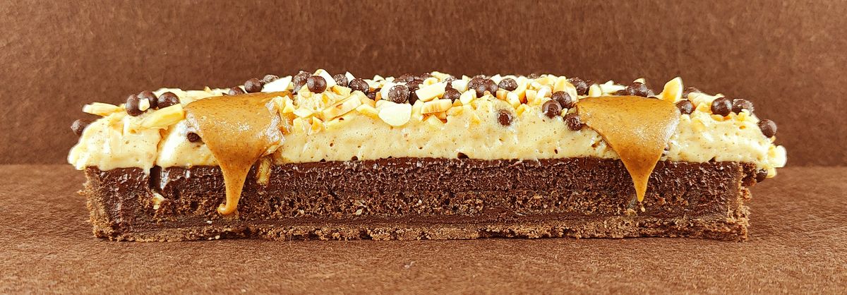 Porción individual rectangular de Tarta Ópera vista de frente, con sus capas alternas de bizcocho de almendra, crema de café y ganache de chocolate perfectamente alineadas.