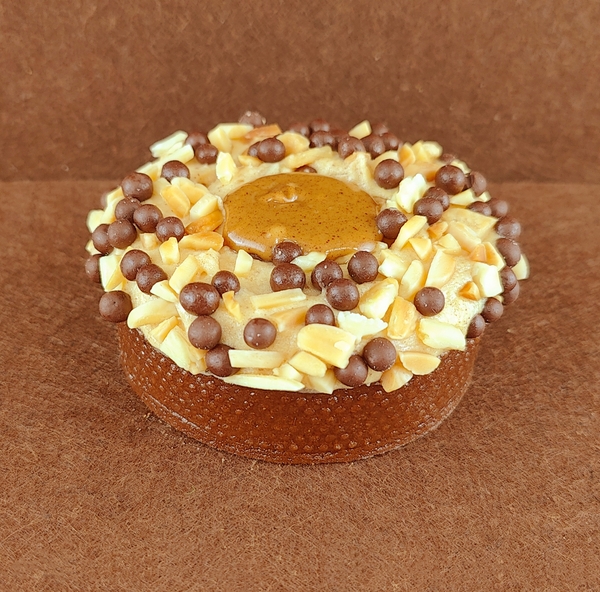 Porción individual rectangular de Tarta Ópera, fotografiada en ángulo de 45 grados con ligera inclinación, mostrando la cobertura de chocolate lisa y un grano de café decorativo en la parte superior.