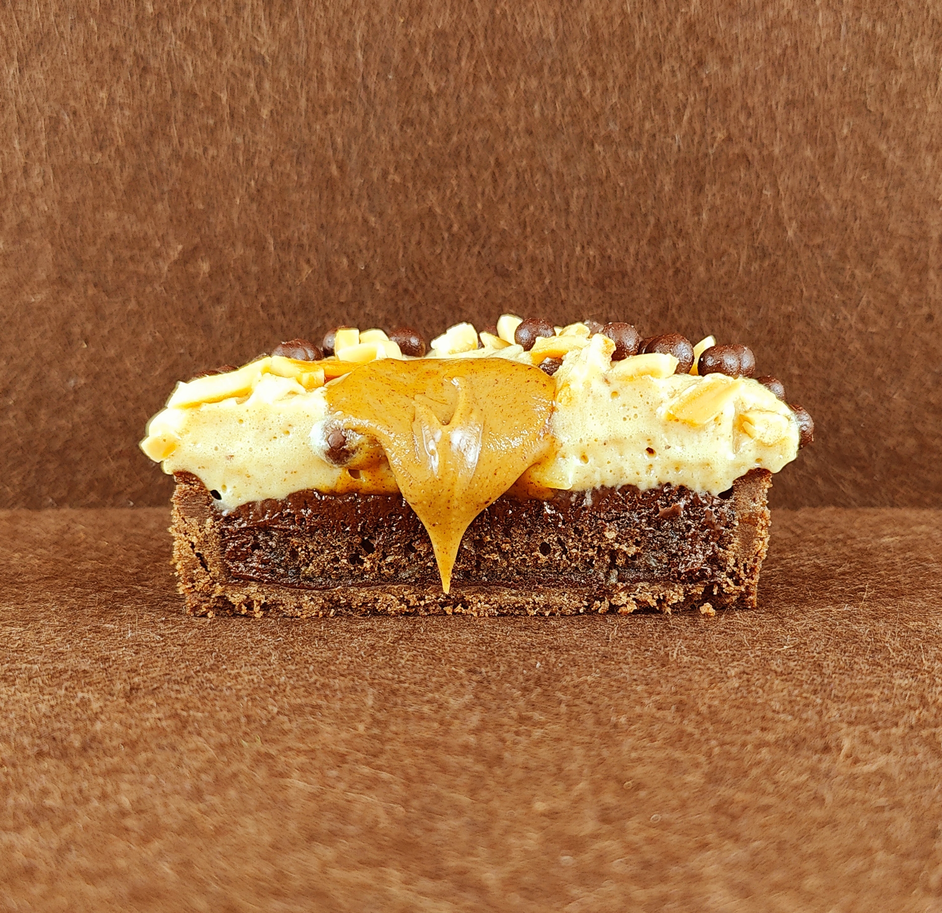 Porción individual rectangular de Tarta Ópera vista de frente, con sus capas alternas de bizcocho de almendra, crema de café y ganache de chocolate perfectamente alineadas.